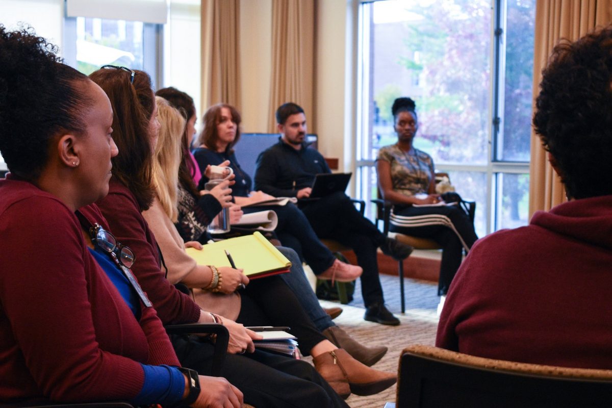 8 adults in semi-circle listen to discussant
