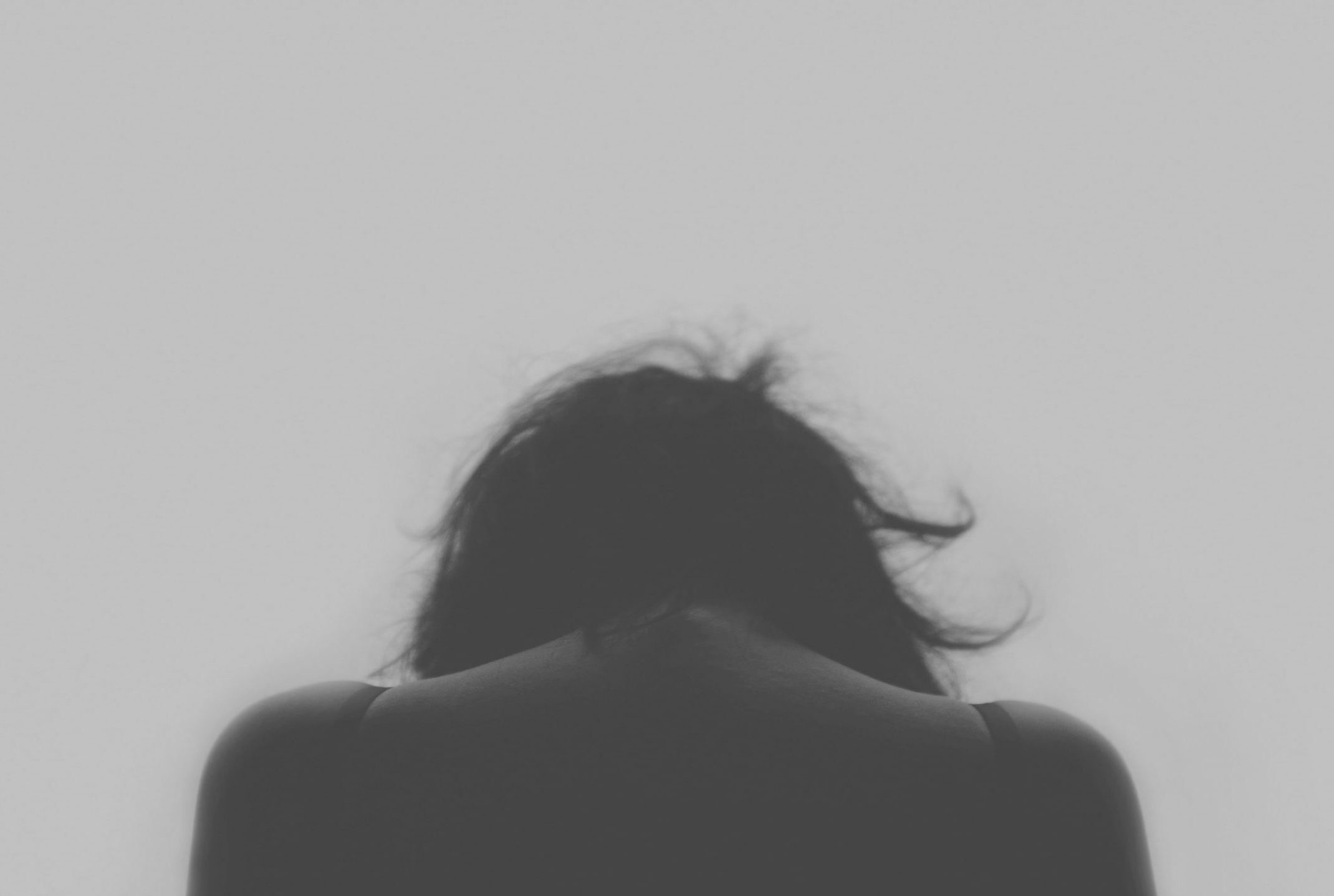 teen girl with back to the camera, with head down; photo is in black and white