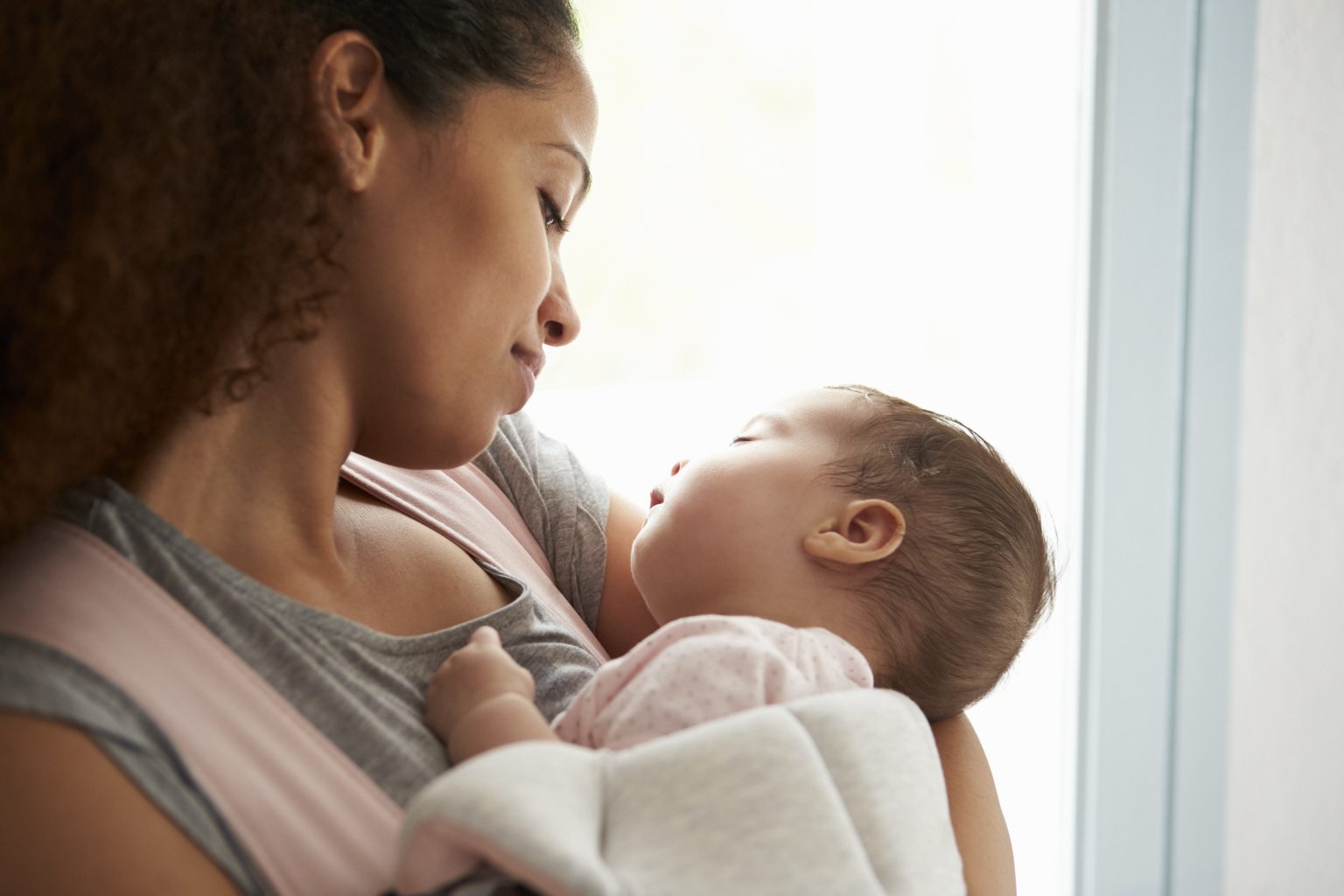 Black mother looking down at infant in her arms with smile