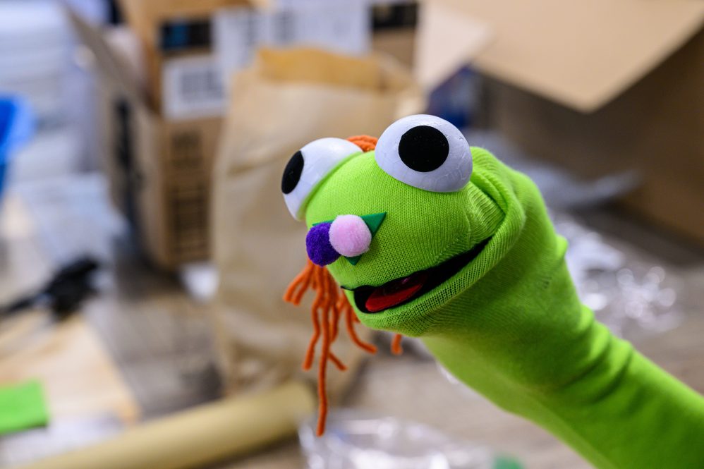DA bright green puppet with large googly eyes, orange hair, and purple and pink nostrils stares at the camera. (Peter Morenus/UConn Photo)