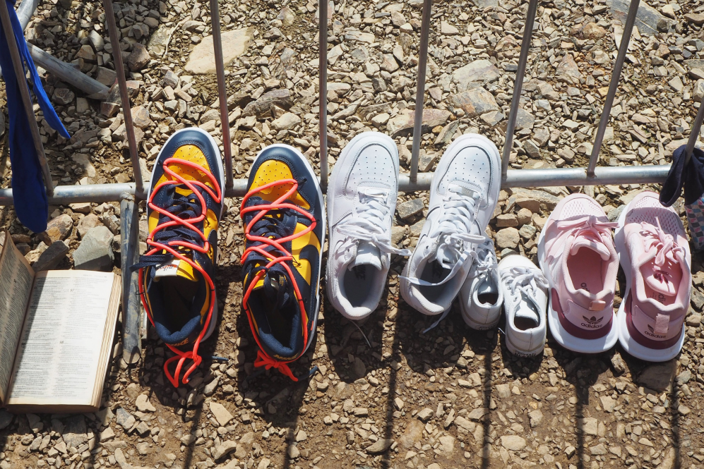 Migrants' shoes and a Bible lined up to dry in a reception center (Photo by Madeline Baird)
